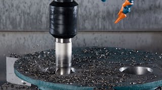A close-up view of the hole-making process shows the Ingersoll Hi-Feed Deka face mill producing chips, partway through a complete hole. The tool withstands the lateral and impact forces associated with corkscrew milling, the developer noted, and because it has twice the diameter of the previous solid-carbide end mill it is less susceptible to deflection, and it leaves no slug.