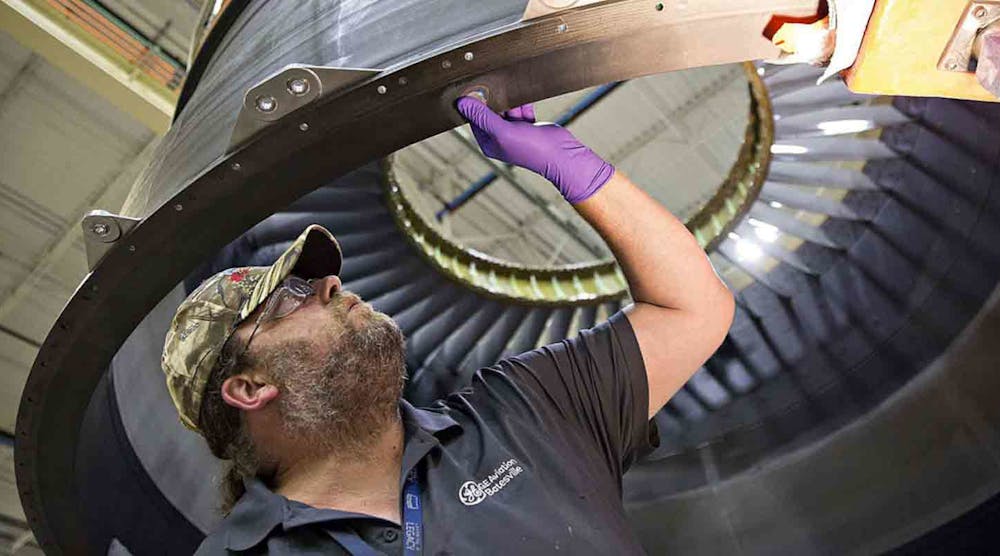 A GE Aviation technician inspects damage to a composite engine case during repair operations.