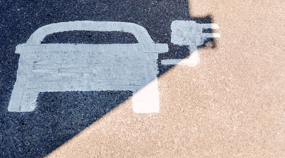 A painted road sign indicates an electric-vehicle recharging parking point.