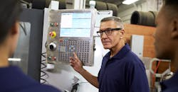 An engineer conducts on-the-floor instruction at a CNC machine. An engineer conducts on-the-floor instruction at a CNC machine.