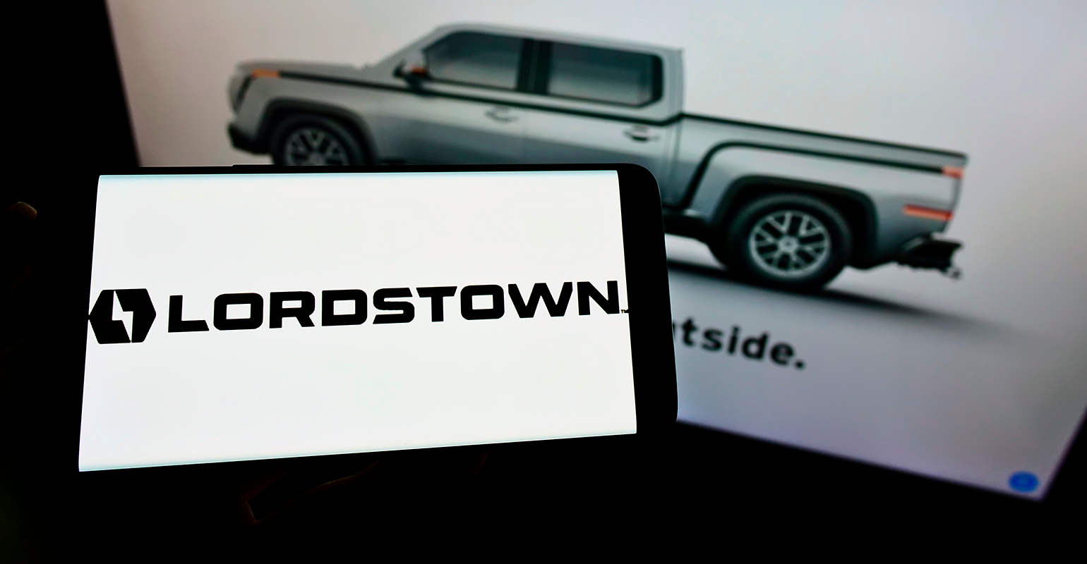 Cellphone with logo of Lordstown Motors Corporation on screen in front of webpage.