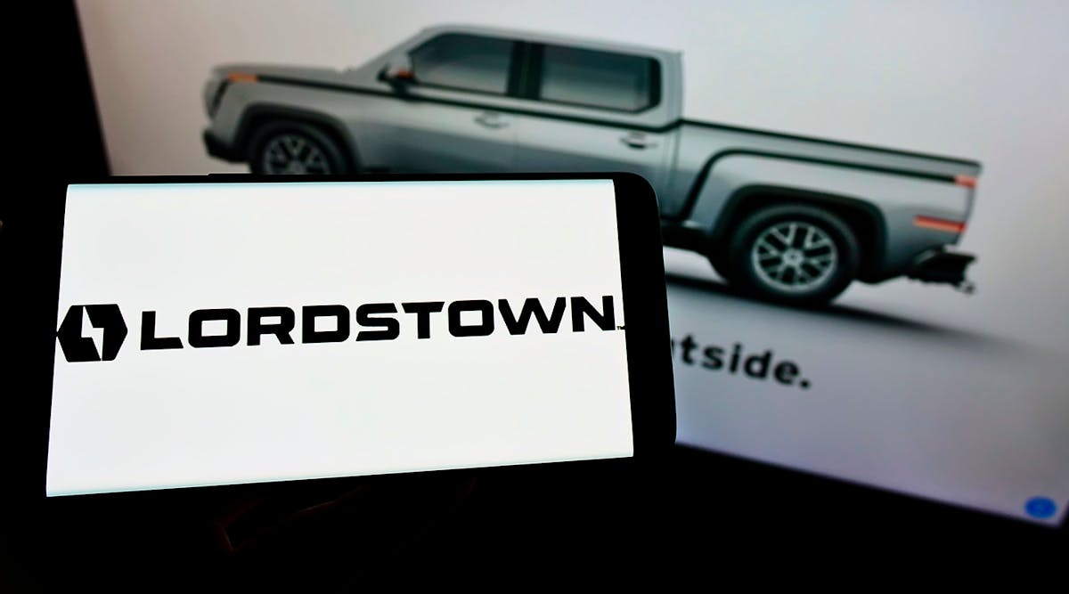 Cellphone with logo of Lordstown Motors Corporation on screen in front of webpage.