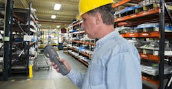 A worker is using a handheld scanner for inventory management control in a manufacturing warehouse operation.