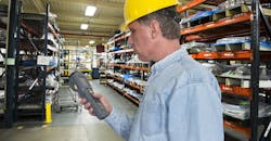 A worker is using a handheld scanner for inventory management control in a manufacturing warehouse operation. A worker is using a handheld scanner for inventory management control in a manufacturing warehouse operation.