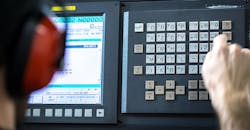 CNC operator, at milling machine center, installing data at a keyboard. CNC operator, at milling machine center, installing data at a keyboard.
