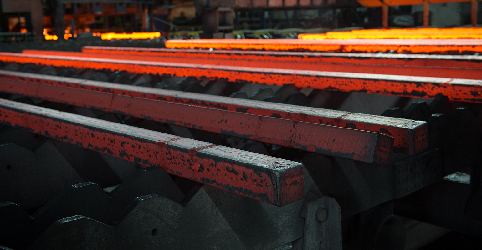 Hot steel billets, cooling on a walking-bed runout table after continuous casting.