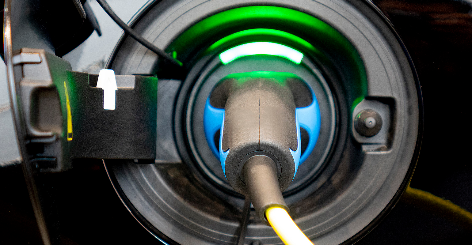 EV at charging station, with the power cable supply plugged.