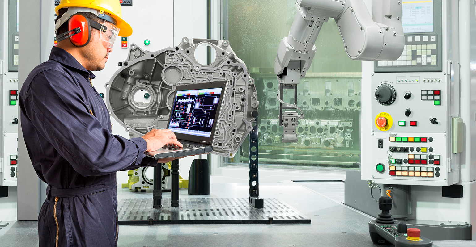 Smart factory concept: Engineer using laptop control with CNC machine in automotive industry.