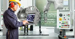 Smart factory concept: Engineer using laptop control with CNC machine in automotive industry.