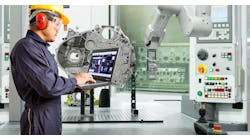 Smart factory concept: Engineer using laptop control with CNC machine in automotive industry.