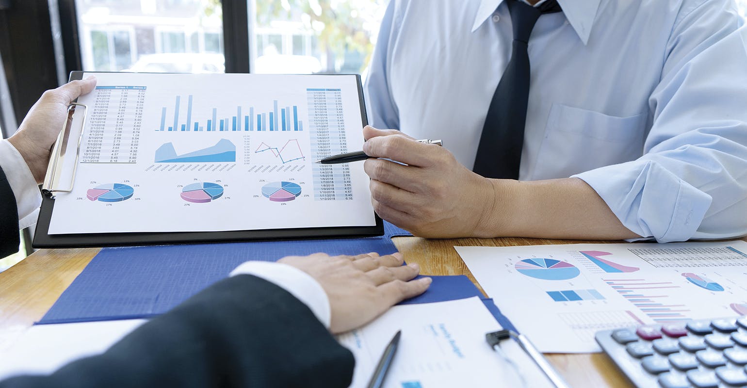 Businessmen evaluating costs and performance charts.