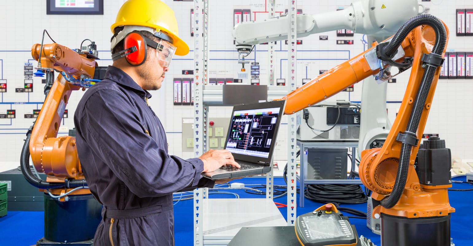 Manufacturing engineer installing and testing a robot.