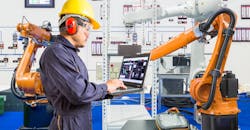 Manufacturing engineer installing and testing a robot. Manufacturing engineer installing and testing a robot.
