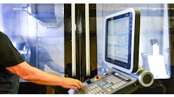 Operator at the control panel of a high-precision CNC machining center. Operator at the control panel of a high-precision CNC machining center.