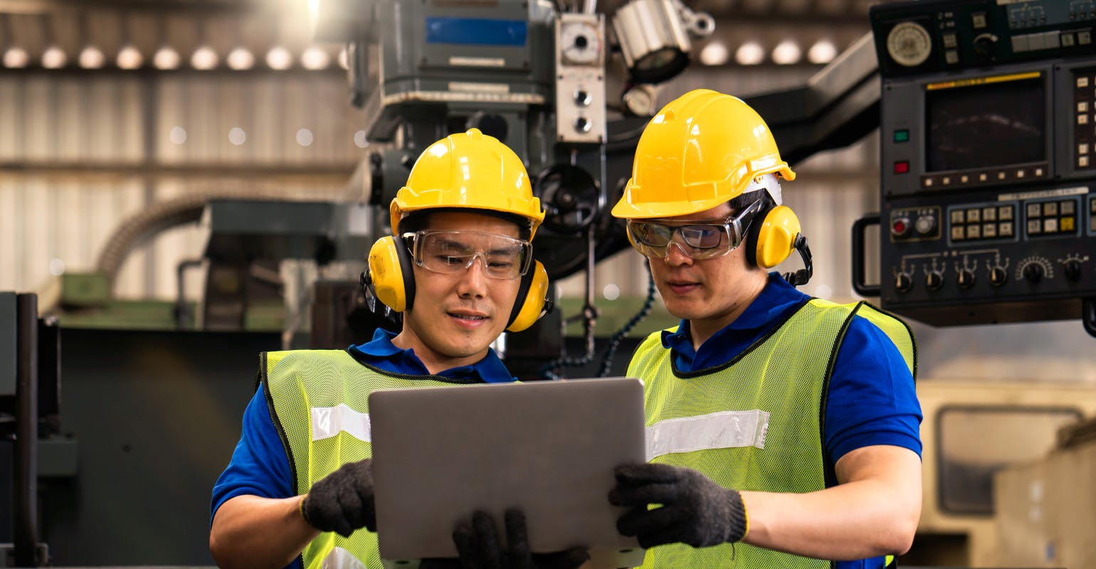 Technicians / engineers inspecting machine operations using a laptop computer.