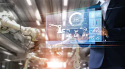 Manager / industrial engineer using a tablet checks and controls automation robot arms and machines in an intelligent factory.