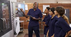 Experienced engineer training apprentices on a CNC machine Experienced engineer training apprentices on a CNC machine