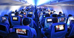 Airline passengers flying coach on a commercial flight with built in screens. Airline passengers flying coach on a commercial flight with built in screens.