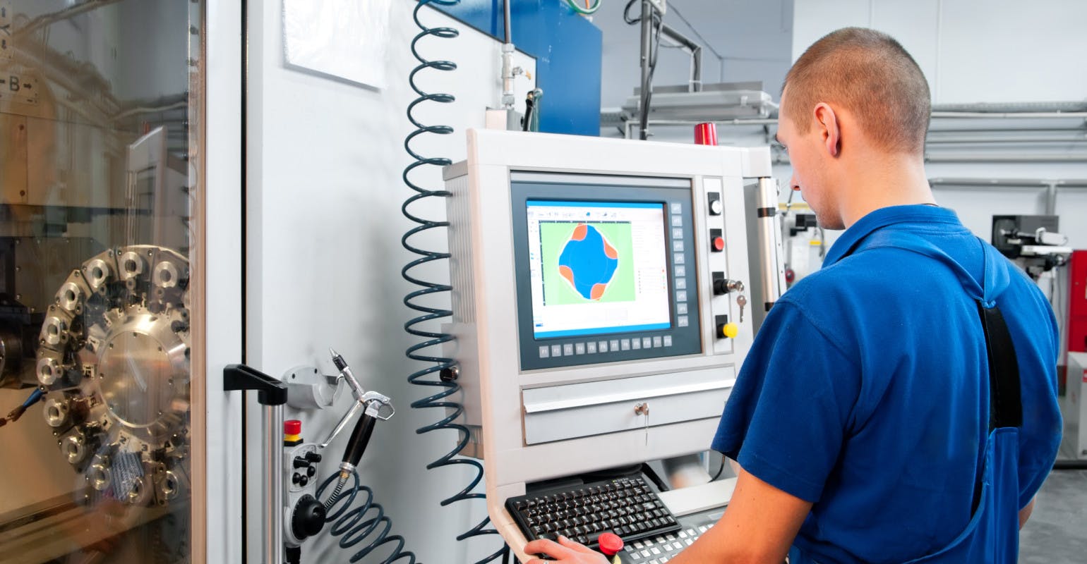 Worker operating CNC machine center.