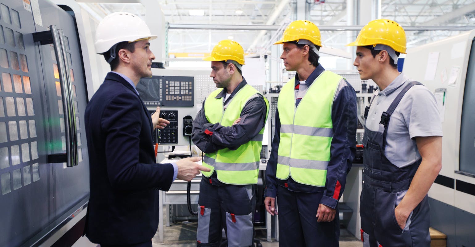 Manager and workers at plant near CNC machines