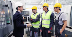 Manager and workers at plant near CNC machines Manager and workers at plant near CNC machines