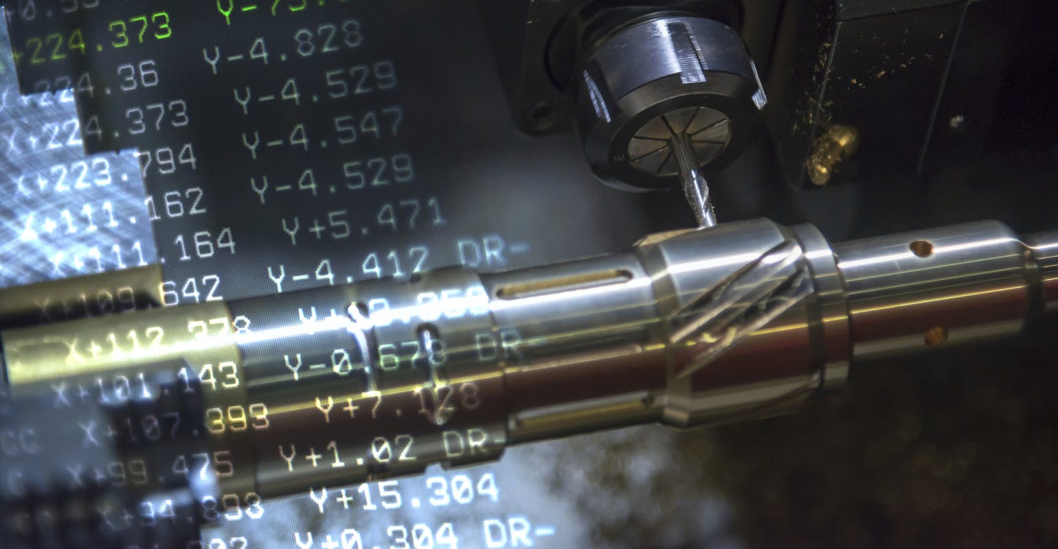 CNC turning machine cutting groove, with G-code data in background.