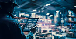 Worker manages industrial warehouse with digital tablet.