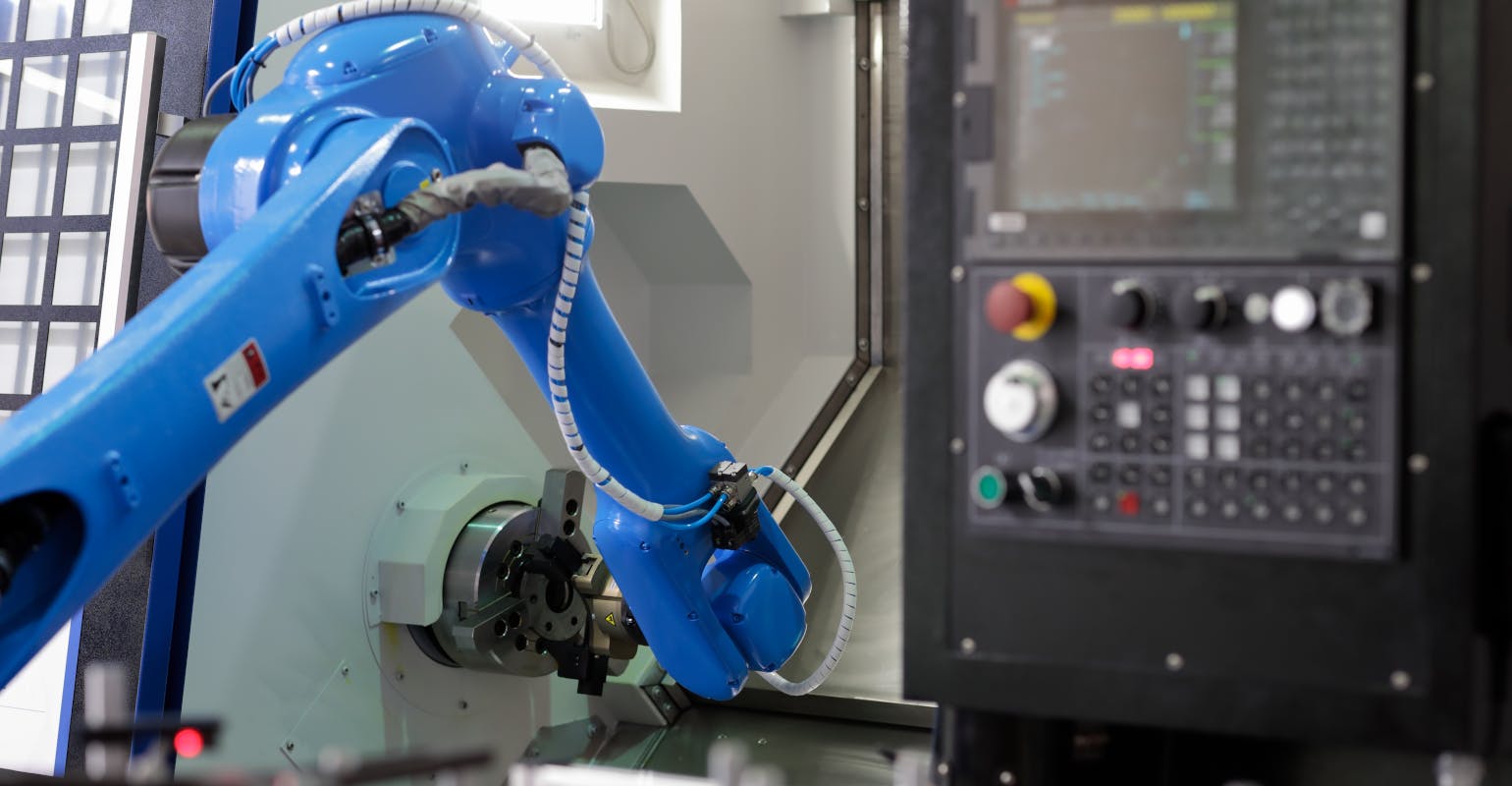 Robot loading parts into CNC lathe machine.