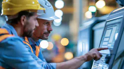Engineer and apprentice working together on a computerized cutting machine.