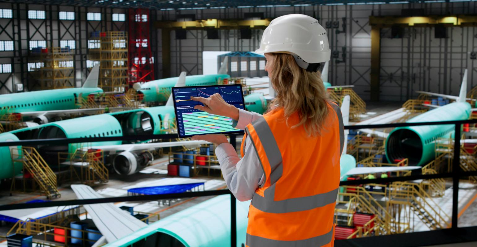 Aerospace engineer using SCADA software in factory checks airplane panels.