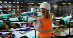 Aerospace engineer using SCADA software in factory checks airplane panels.