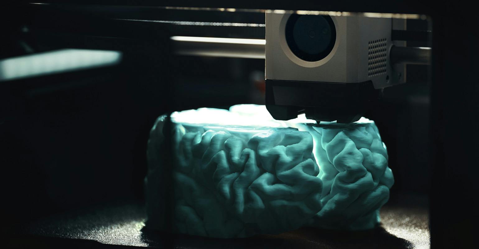 3D printing of a cyan human brain model.