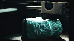 3D printing of a cyan human brain model.