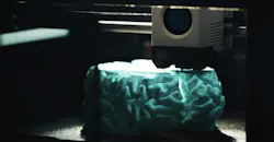 3D printing of a cyan human brain model.