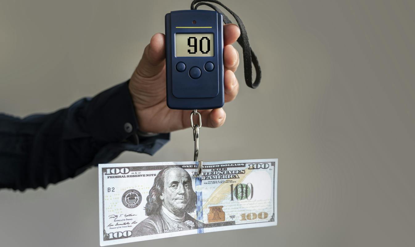 Weighing operating costs, dollar bill on electronic scales.